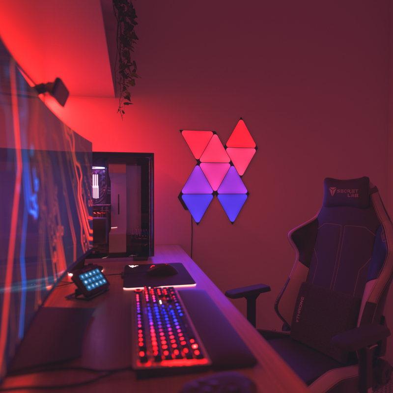 Nanoleaf Shapes Thread enabled color changing black triangle smart modular light panels mounted to a wall next to a battlestation. Similar to Philips Hue, Lifx. HomeKit, Google Assistant, Amazon Alexa, IFTTT.